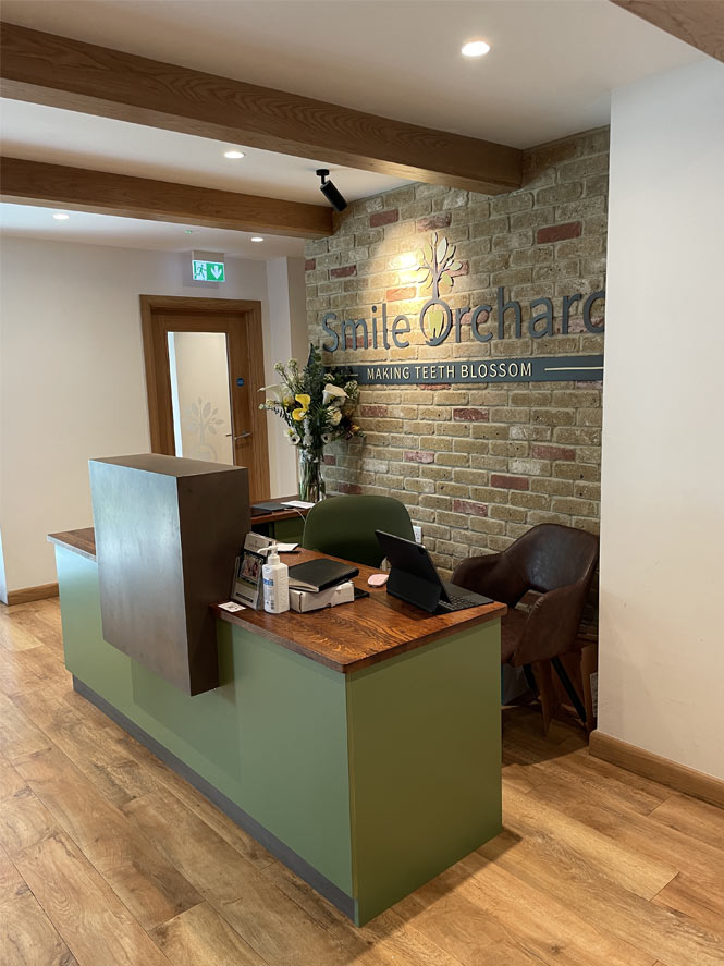 Smile Orchard green reception desk with brick wall behind Joseph King Interiors Bristol